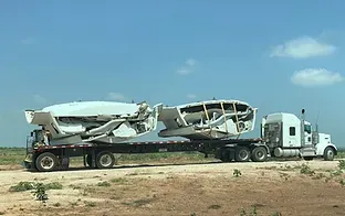 A truck with a trailer carrying an airplane.