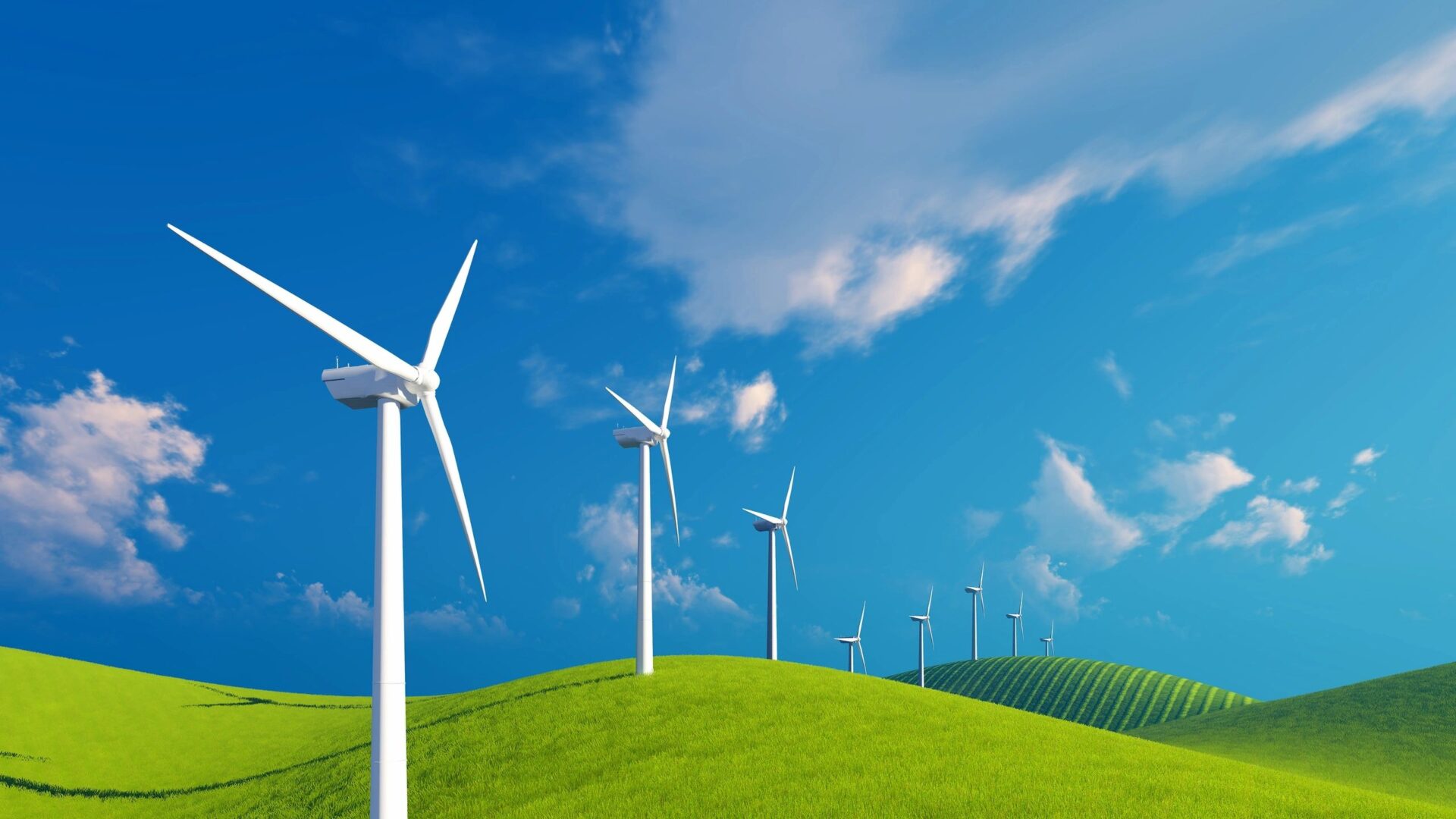 A group of wind turbines on top of a green hill.